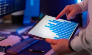 Profissional de negócios analisando gráfico em tablet, destacando estratégias de marketing digital em ambiente de escritório