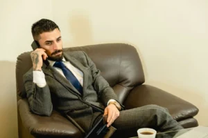 Advogado de terno cinza conversando ao telefone em um escritório moderno, representando o uso do whatsapp para advogados